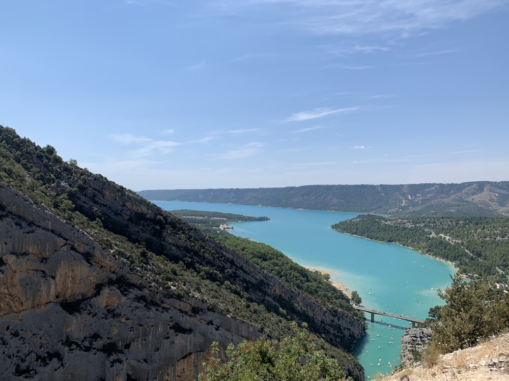 lago verde entre montanhas sob o céu azul durante o dia