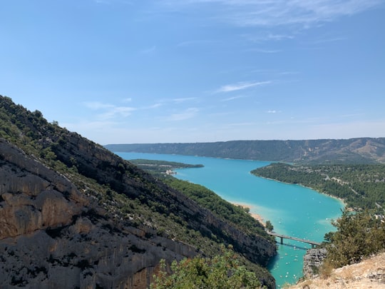 green lake between mountains under blue sky during daytime in Alpes-de-Haute-Provence France