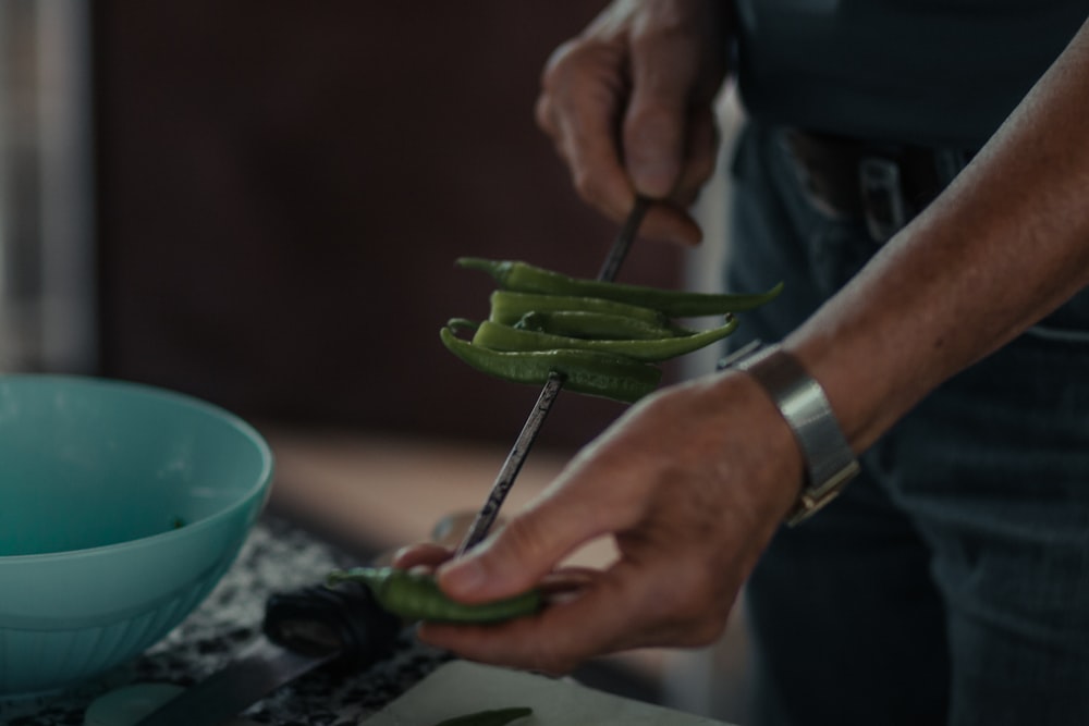 persona sosteniendo una verdura verde en un plato de cerámica verde