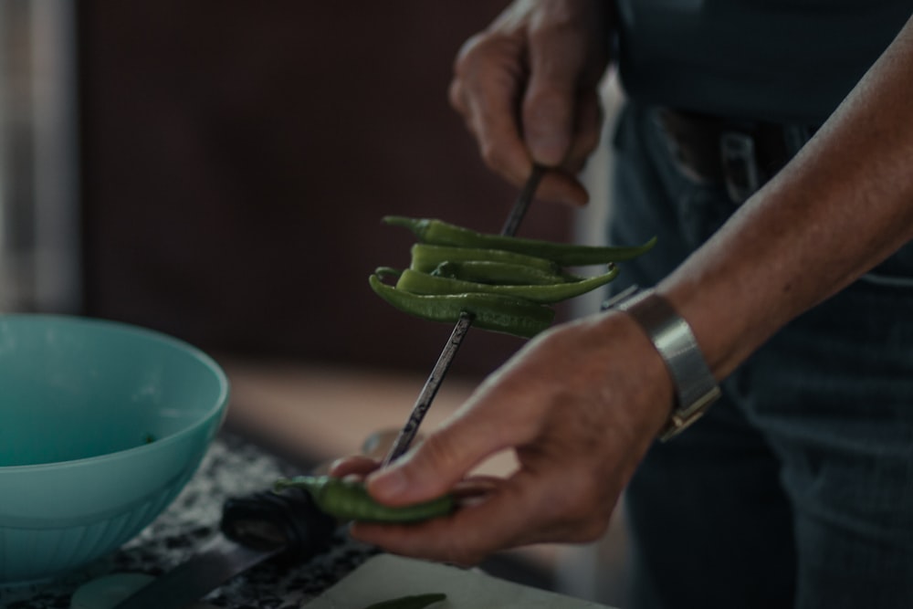 person holding green vegetable on green ceramic plate