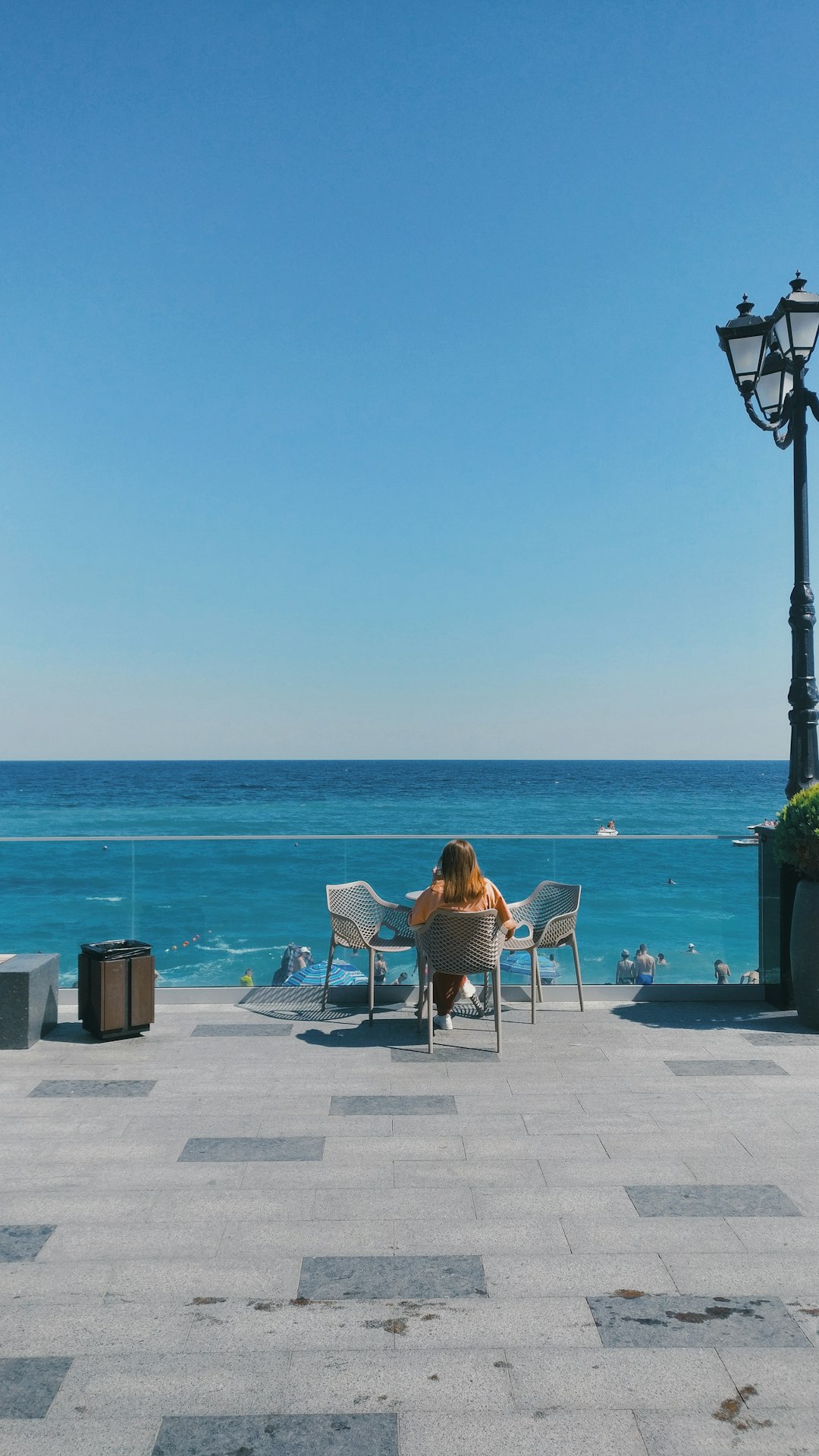 2 person sitting on chair near sea during daytime