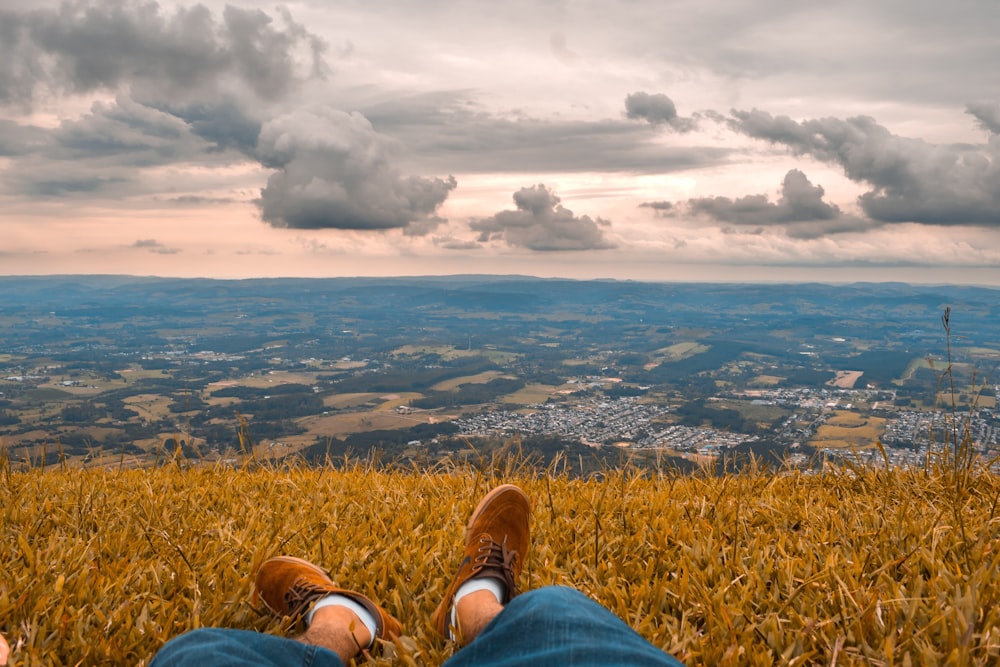 une personne assise au sommet d’un champ couvert d’herbe