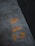 Concrete surface with weathered yellow numbers painted on it, shown in an industrial environment with a dark body of water to the side.