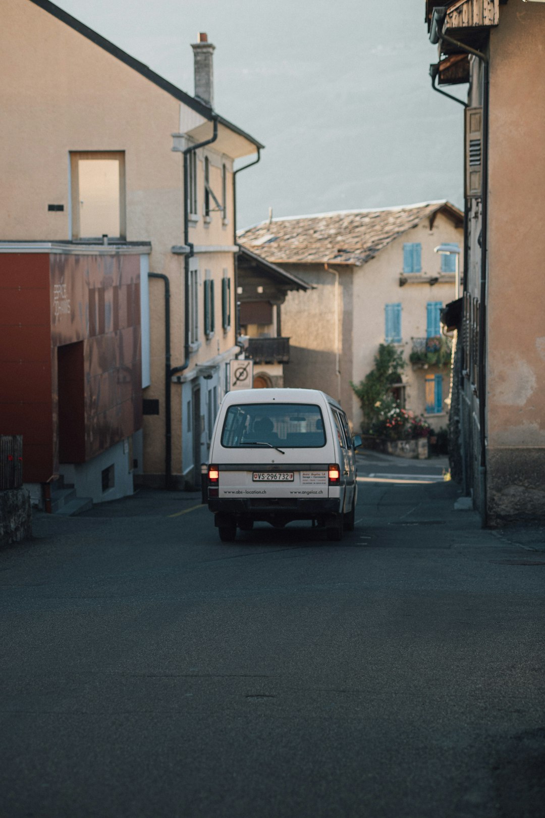 white car parked beside brown building during daytime