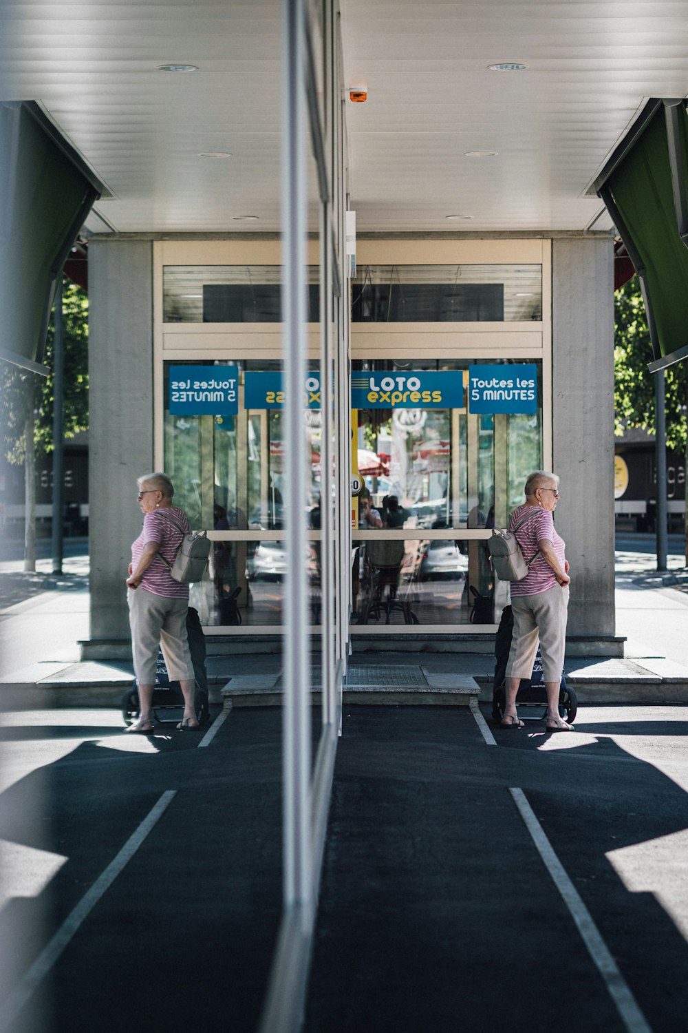 man in white dress shirt and gray pants standing beside glass window during daytime