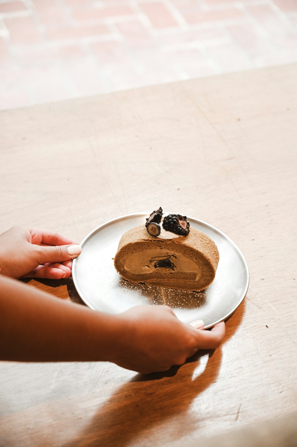 person holding white ceramic plate with brown and black food