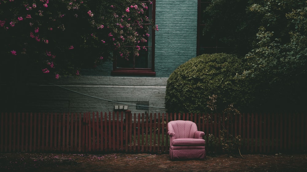 pink padded armchair beside green plants