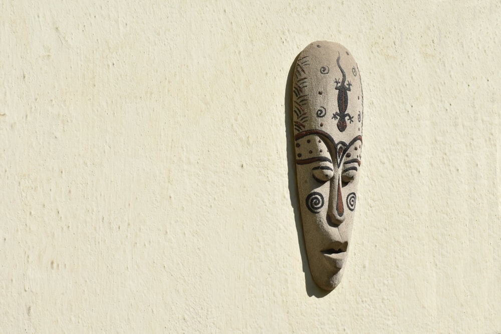 brown wooden mask on white wall