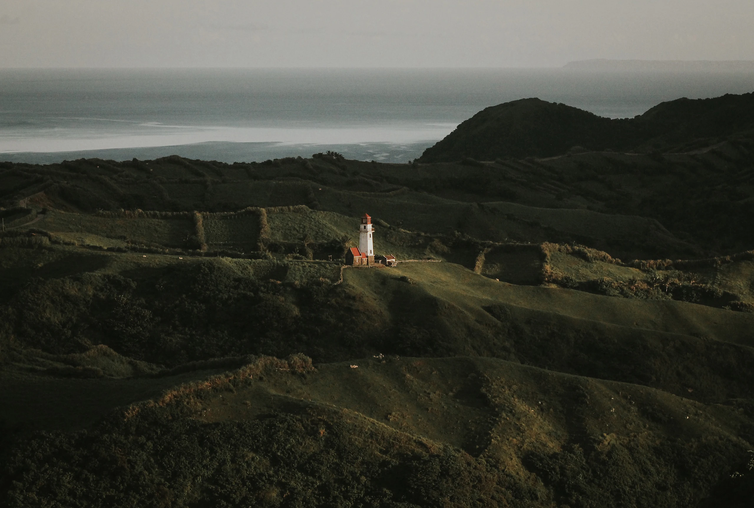 A stone house on a green headland above a rough sea in Batanes