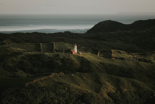 white and red lighthouse on top of mountain in Batanes Philippines