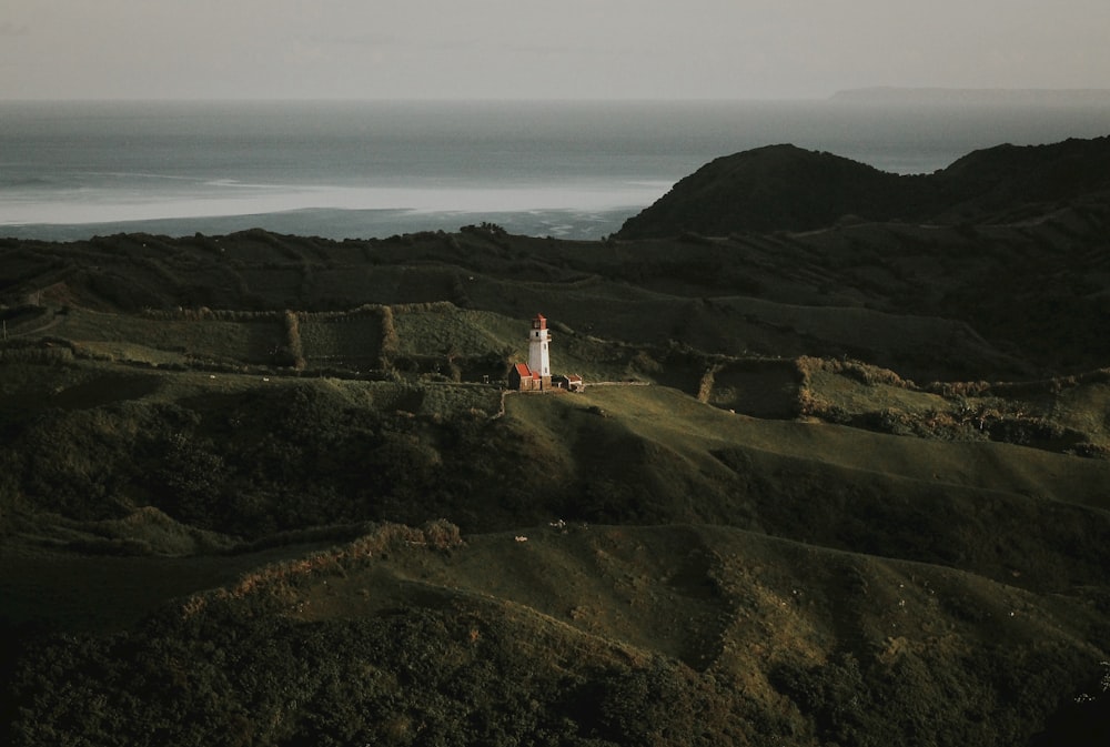 white and red lighthouse on top of mountain