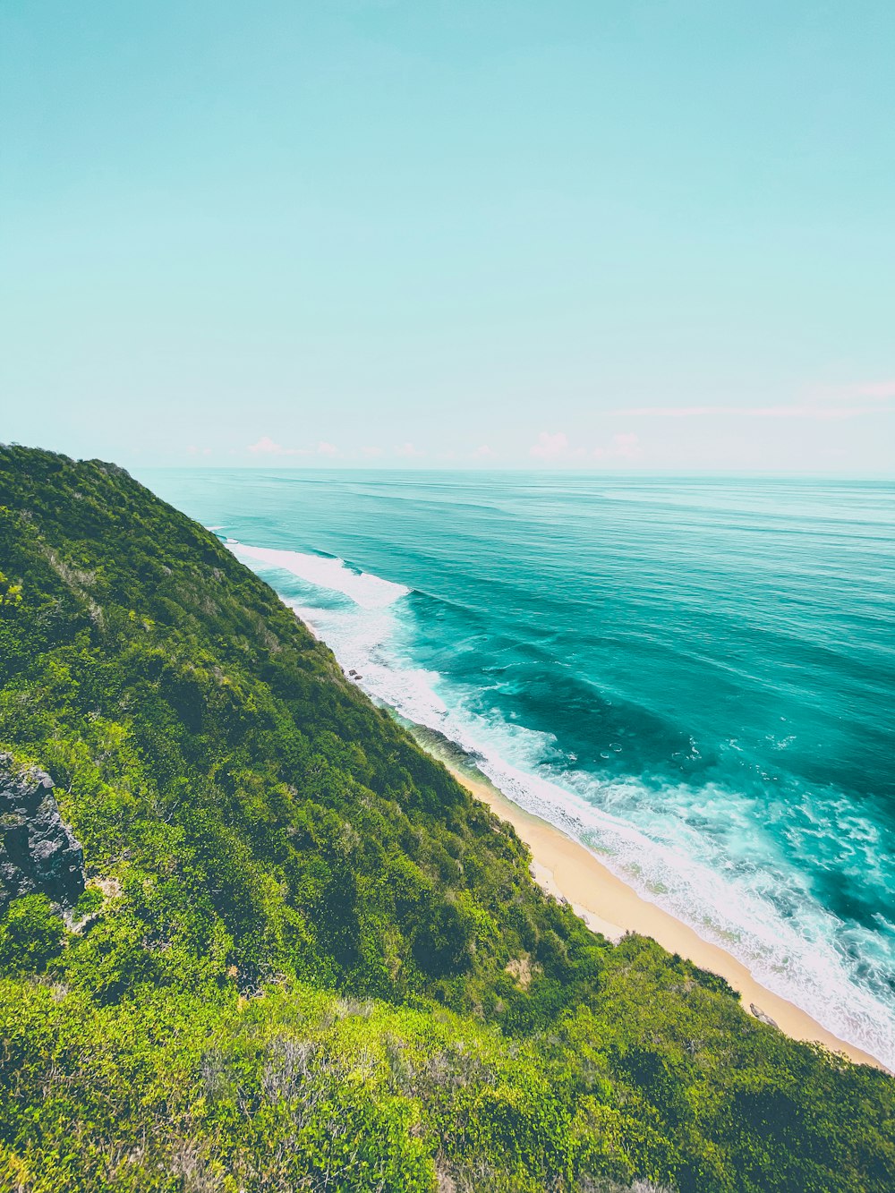 green grass covered mountain beside sea during daytime