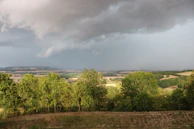 A wide-angle shot of rolling hills under dramatic storm clouds just before rain.