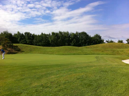 Professional athlete practicing putting with Iniputter technology on a sunny day.