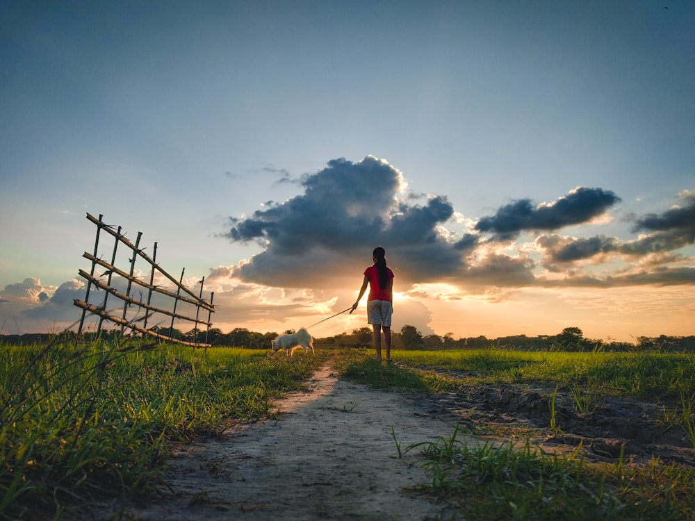 man in red shirt walking on dirt road during daytime