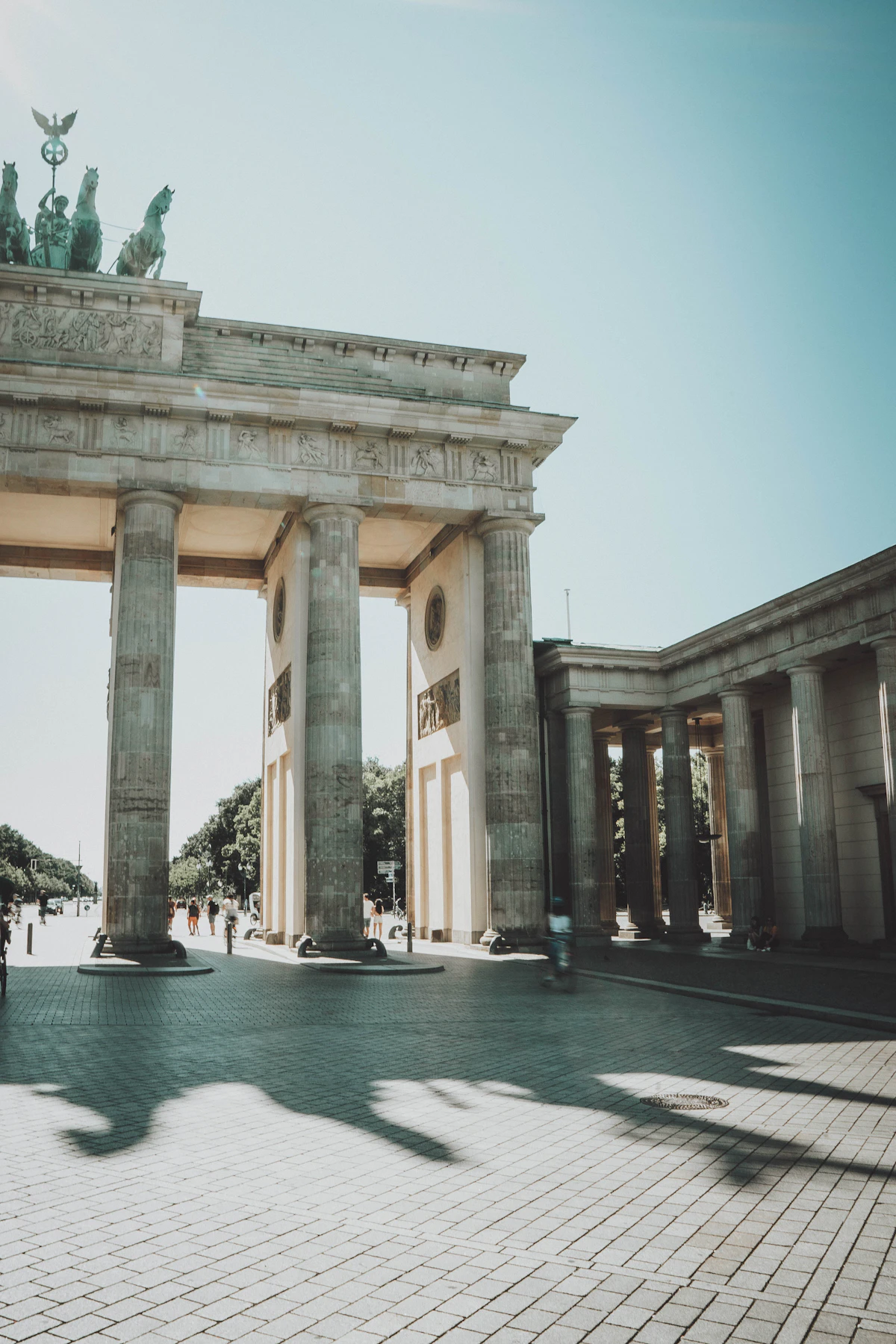 The Brandenburg Gate in Berlin, its neoclassical columns and Quadriga statue lit by daytime sun