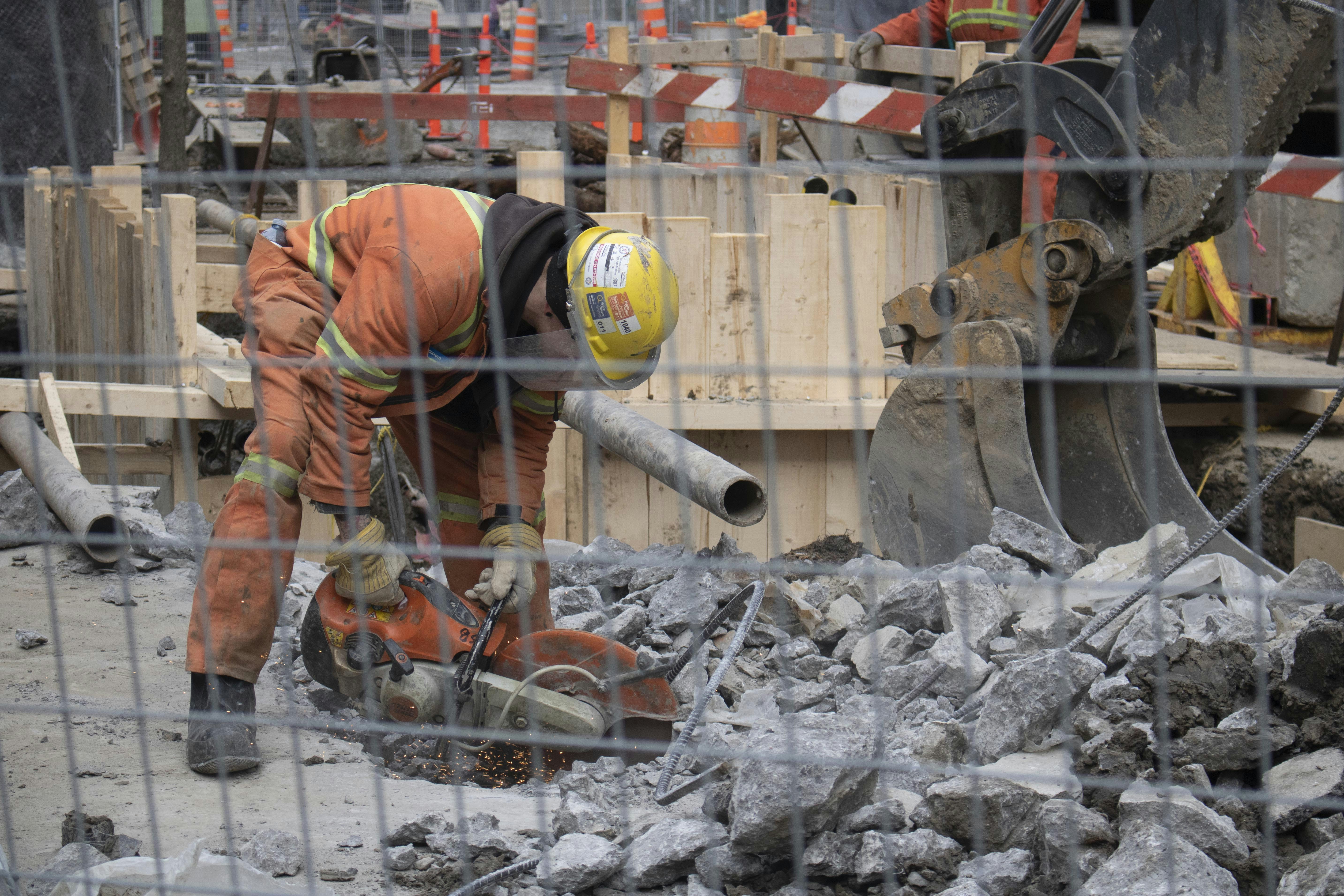 Industrial concrete floor sawing machine in action on a Melbourne construction site, dusty atmosphere, orange safety equipment, dark grey concrete