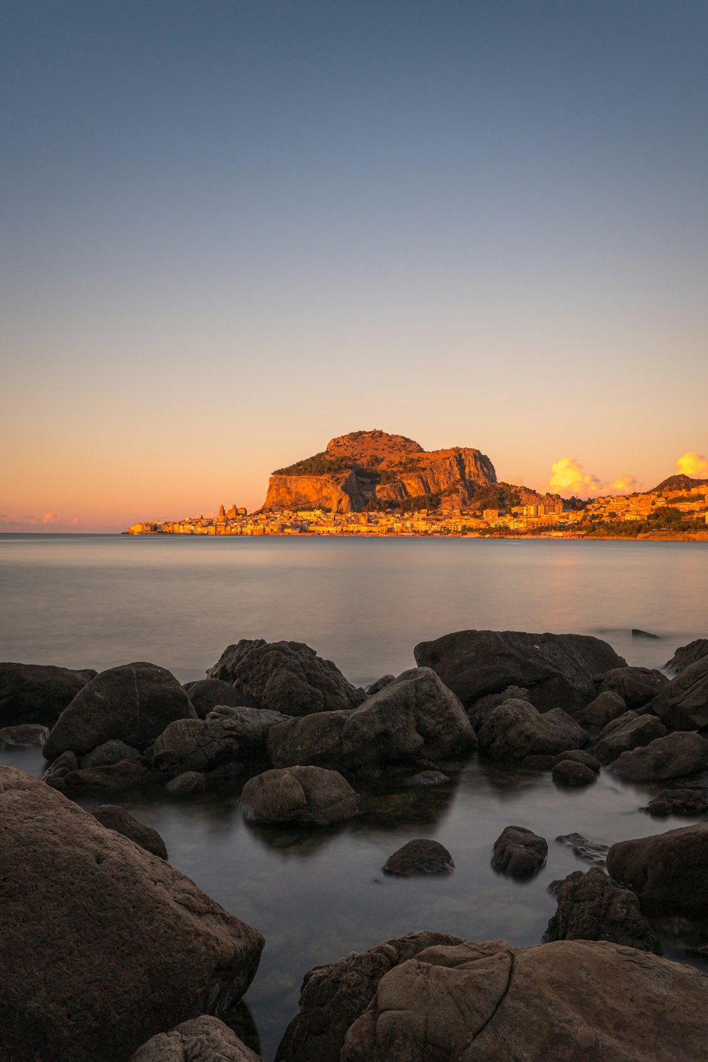 brown rock formation on sea during sunset