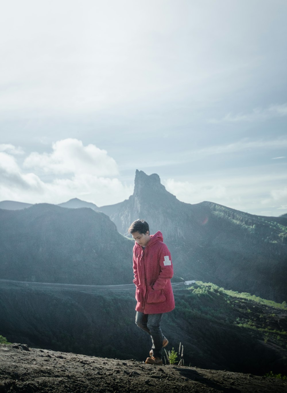 Frau in roter Jacke tagsüber auf dem Gipfel des Berges