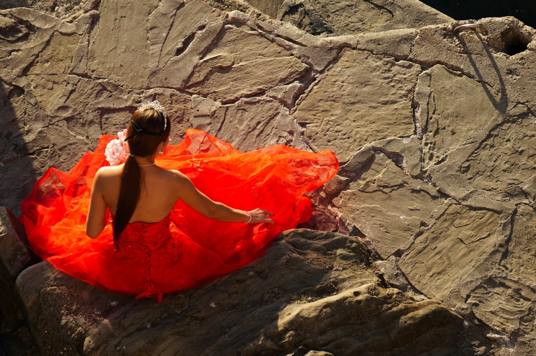 woman in orange tube dress sitting on rock