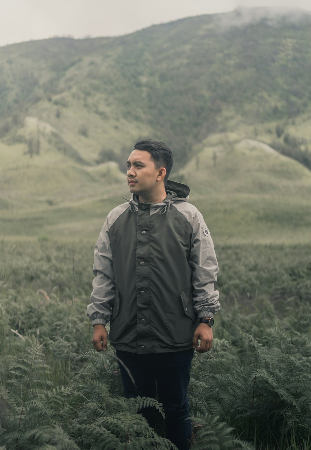 man in gray jacket standing on green grass field during daytime