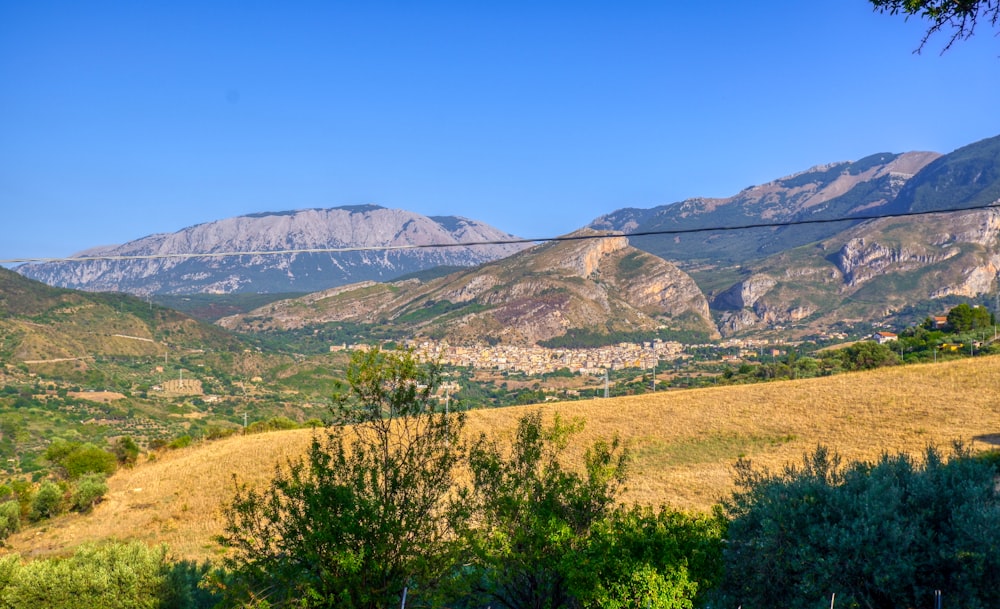 green grass field near mountain under blue sky during daytime