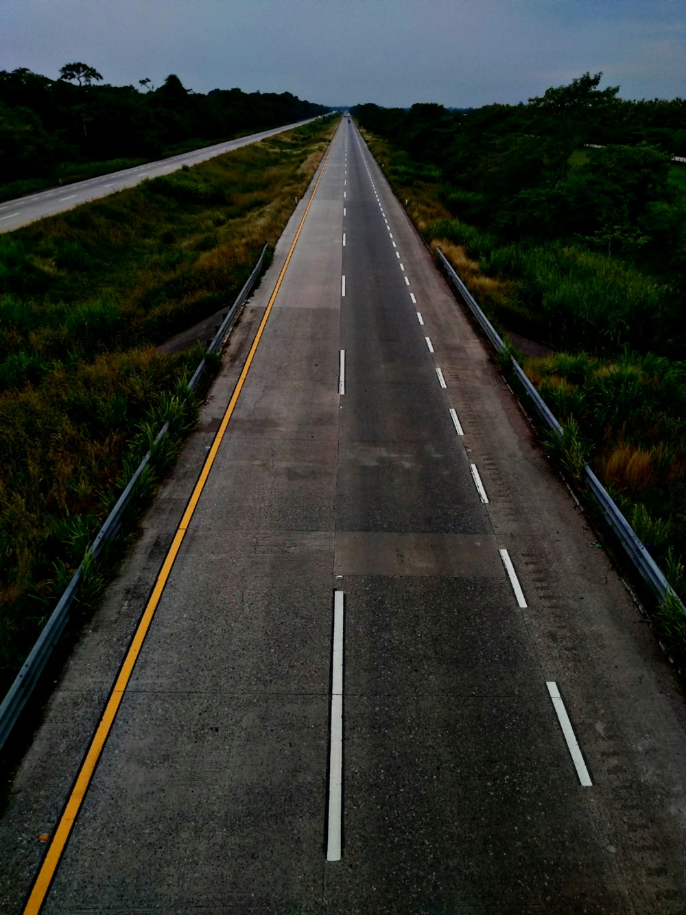estrada de concreto cinza entre grama verde durante o dia
