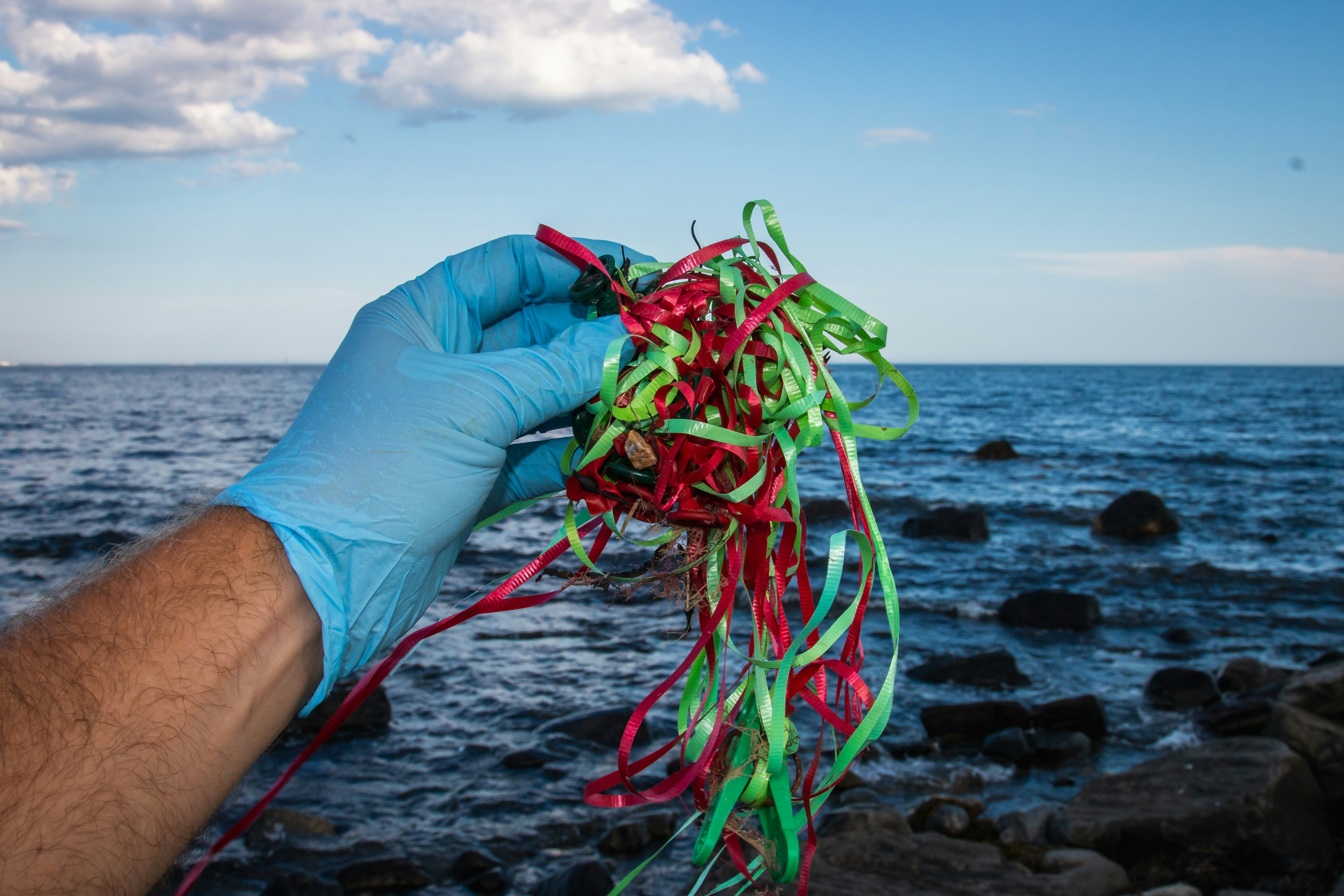 Close-up of microplastics on a researcher's gloved hand, tiny fragments of various colors