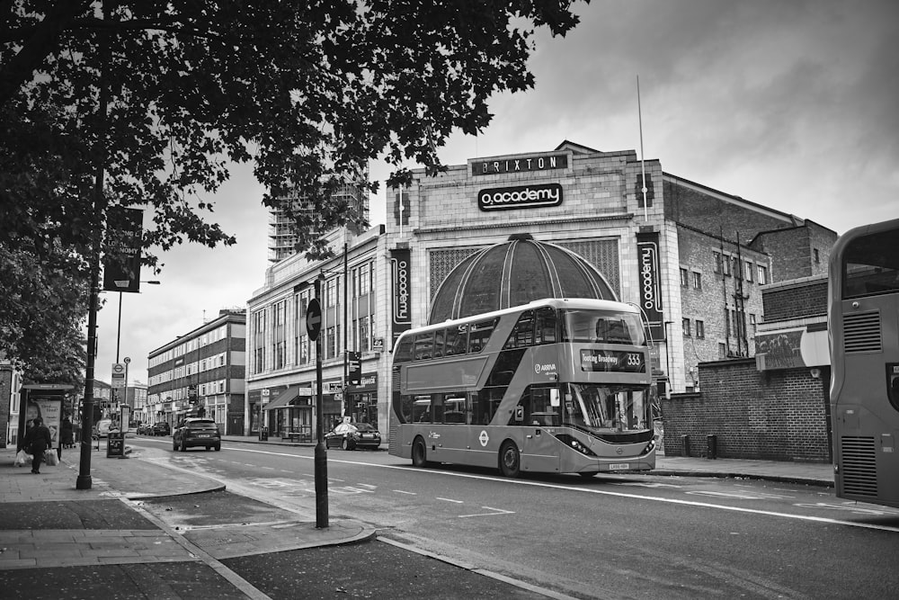 grayscale photo of bus on road near building