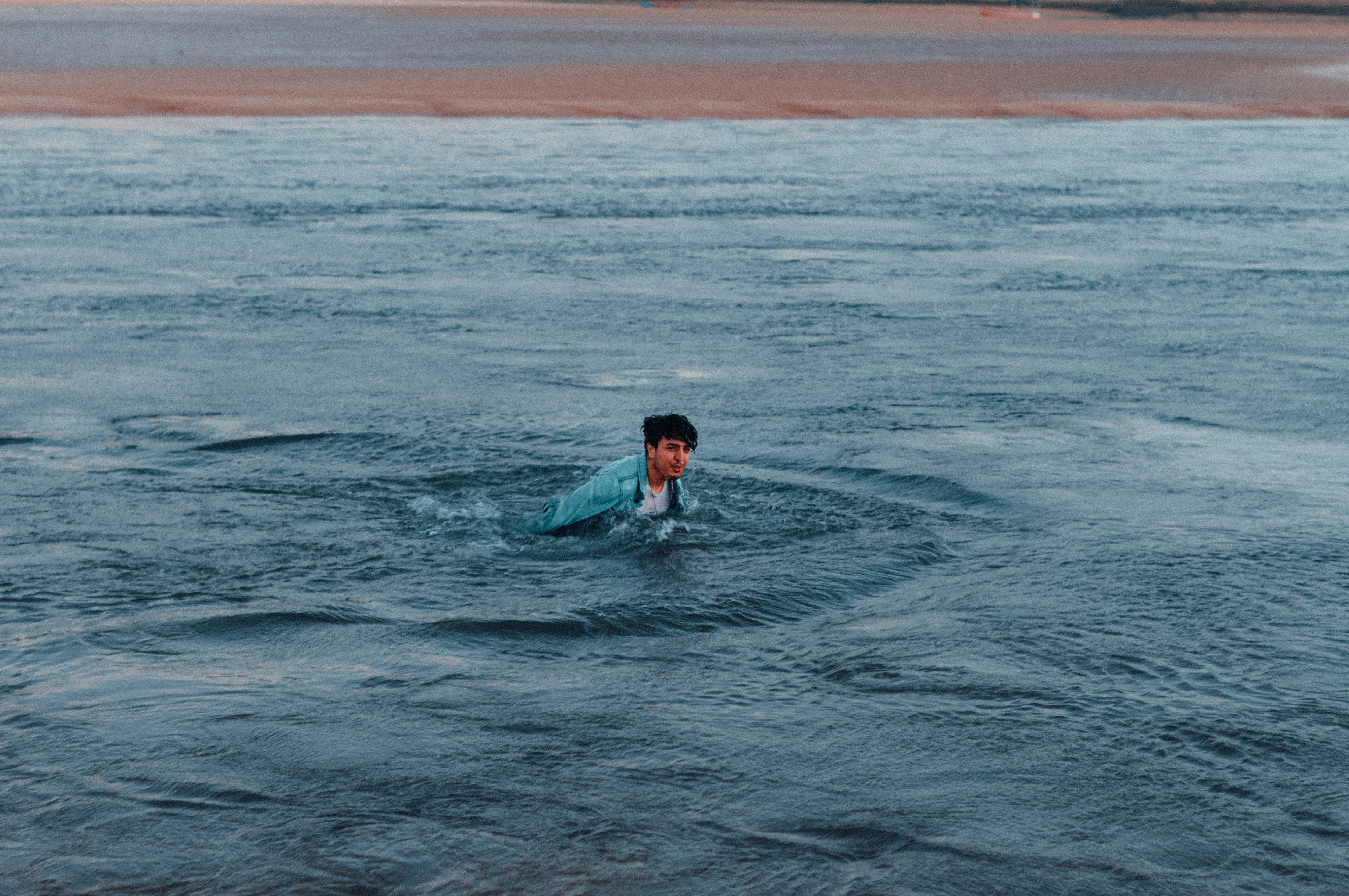 man in blue shirt swimming on sea during daytime