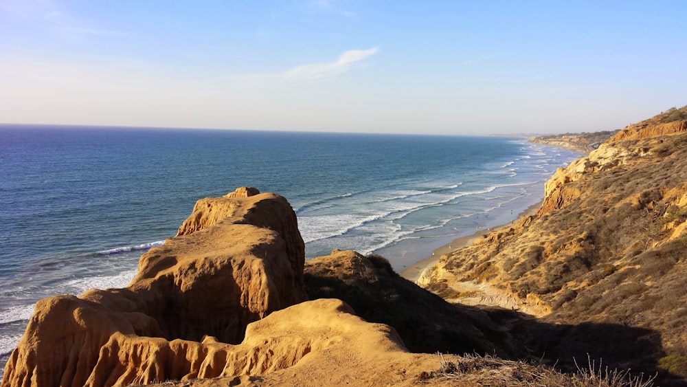 brown rock formation near body of water during daytime