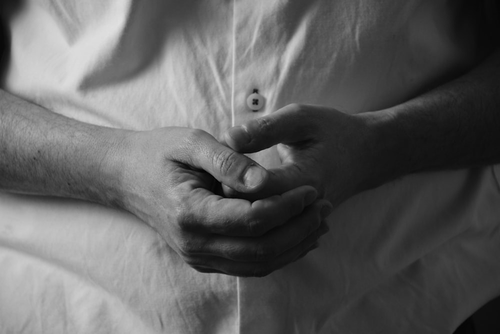 grayscale photo of persons hand on white textile