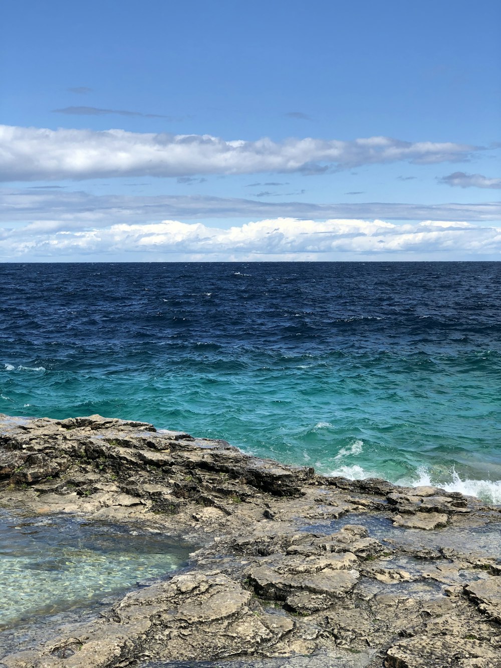 blue ocean water under blue sky and white clouds during daytime
