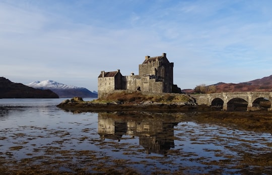gray concrete building near body of water during daytime in Eilean Donan Castle United Kingdom