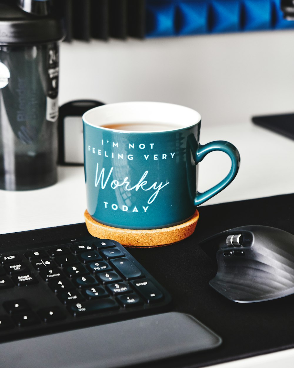 Tasse en céramique verte et blanche à côté du clavier d’ordinateur noir