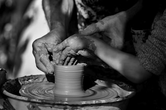 person making clay pot on round clay pot