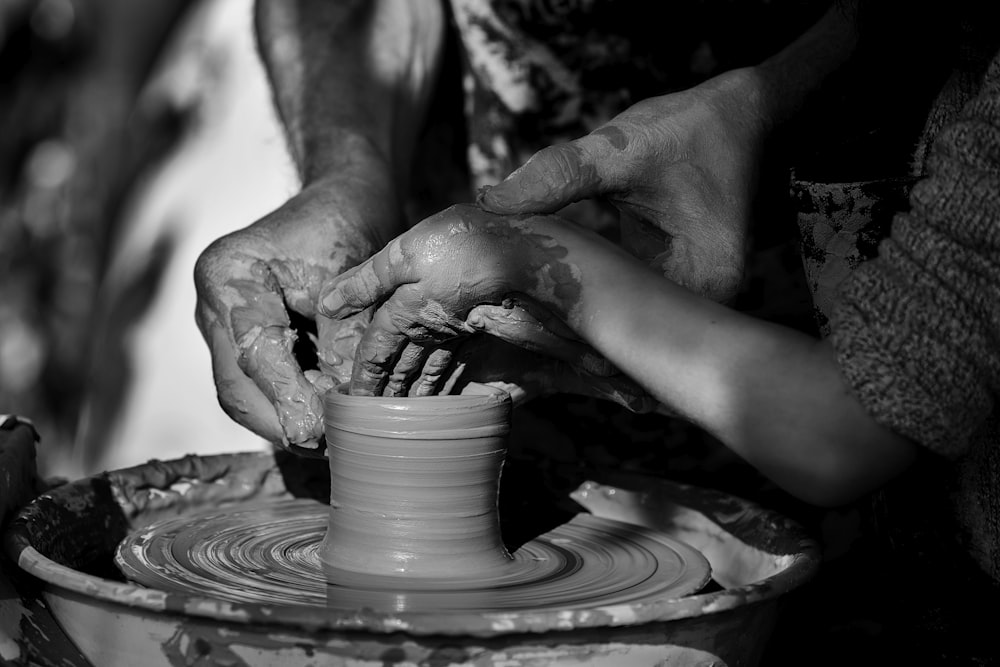 person making clay pot on round clay pot