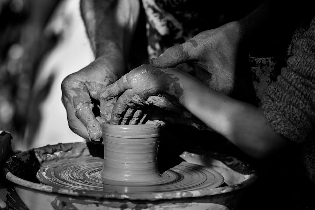person making clay pot on round clay pot