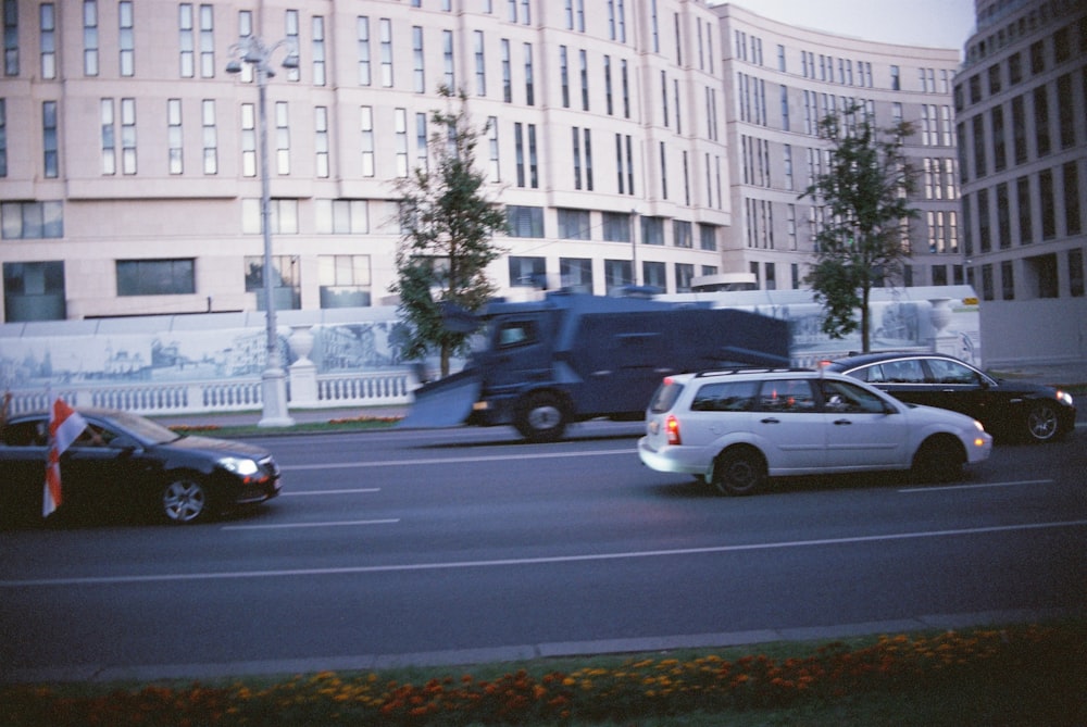 cars parked on side of the road near white concrete building during daytime