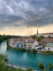 houses near body of water under cloudy sky during daytime