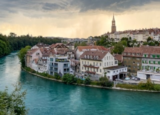 houses near body of water under cloudy sky during daytime