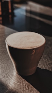 Minimalist photo of a steaming cup of coffee on a white table with soft natural light
