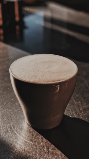 Close-up of steaming coffee cup surrounded by natural elements and soft golden light.