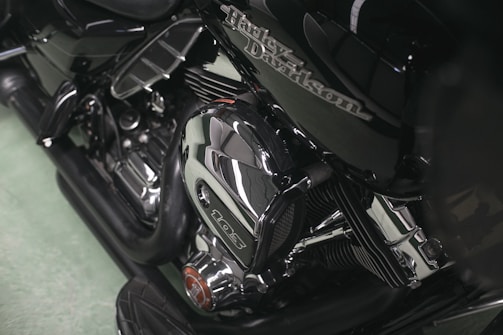 A close-up view of a motorcycle engine featuring polished chrome components and intricate detailing. The Harley-Davidson logo is visible on the side, emphasizing the craftsmanship of the machine.