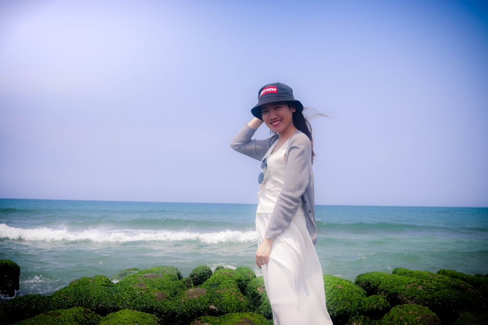 woman in white long sleeve dress standing on green grass field near body of water during