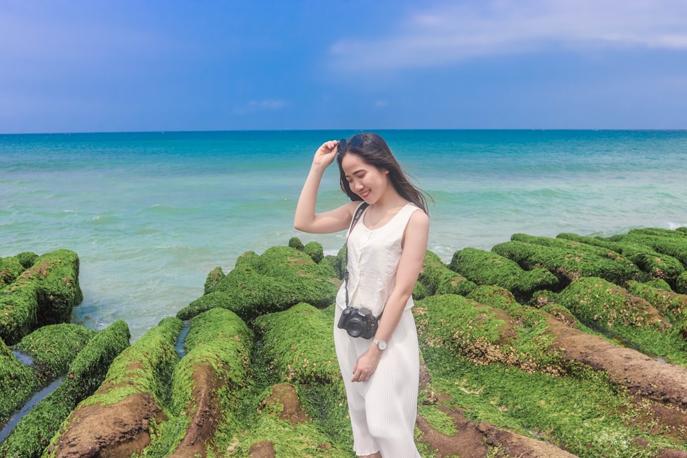 woman in white dress standing on green grass near body of water during daytime