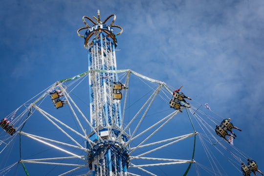 people riding on white and blue ferris wheel under blue sky during daytime in Olympiapark West Germany