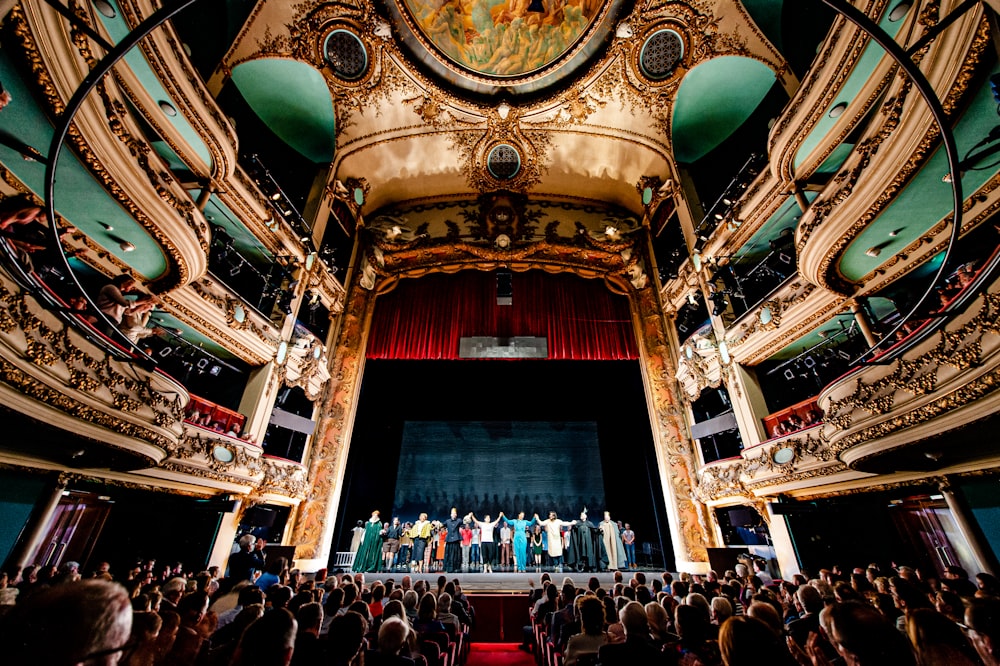 theater cast on stage with a large audience
