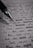 A close-up image of a lined page containing handwritten text with a black pen placed diagonally across it. The text is in cursive script and includes various sentences written in English. The image is in black and white, highlighting the contrast between the ink and the paper.