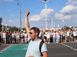 man in white and black crew neck t-shirt raising his right hand